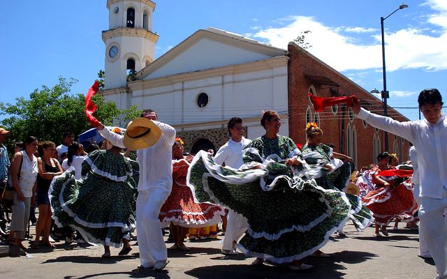 Parejas bailando danza folcl&oacute;rica con trajes t&iacute;picos frente a la iglesia de Melgar