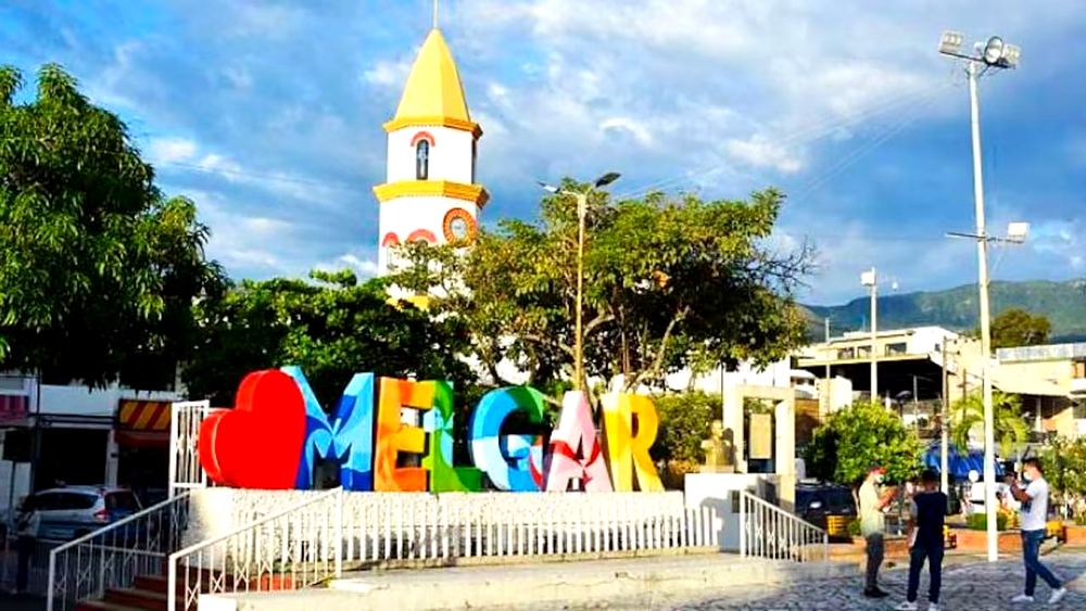 Letrero de letras de colores con el nombre Melgar en la plaza principal, con la iglesia de fondo