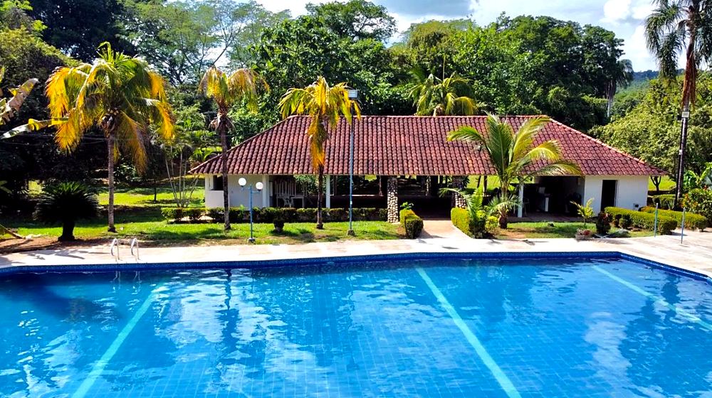 Piscina rodeada de palmeras y zonas verdes en un club de Melgar, Tolima